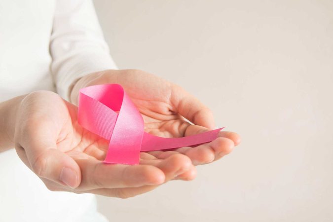 A nurse holding a breast cancer awareness ribbon
